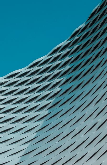 Curved facade of a modern building with a louvered surface against a clear sky